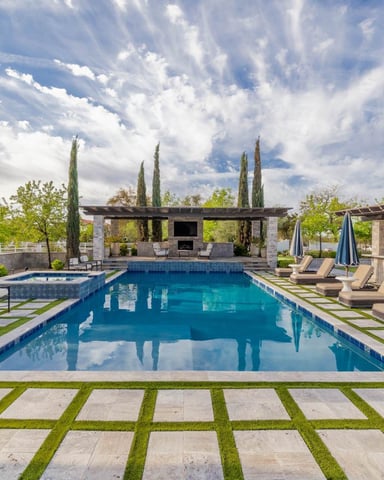 Resort-style pool with pergola, cypress trees, and lounge chairs under a dramatic Arizona sky