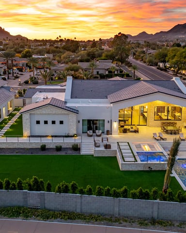 Aerial view of a luxury Paradise Valley estate at sunset with mountains and glowing pool