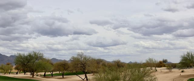 Desert golf course with sand bunkers, green fairway, and Arizona mountains in the background
