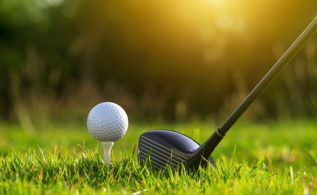Golf ball on tee with driver at sunrise