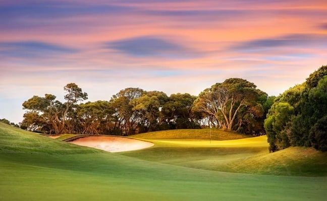 Golf course at sunset with sand bunker and flag