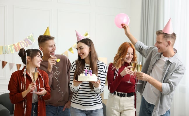 Friends celebrating birthday with cake and balloons