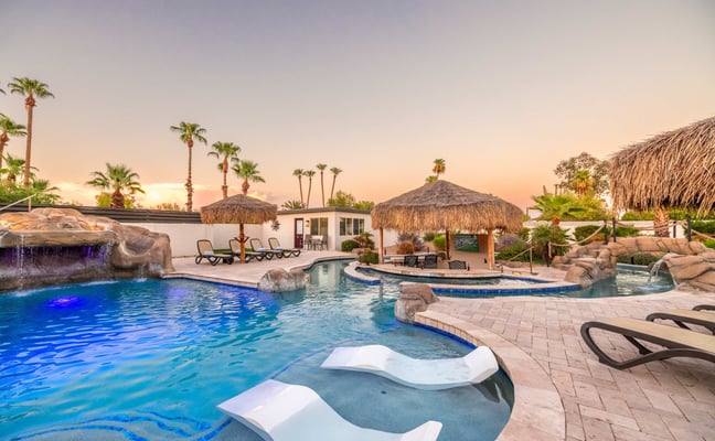 Resort-style pool with pergola, cypress trees, and lounge chairs at a Scottsdale vacation home